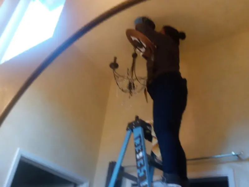 Electrician installing a chandelier in a Stilwell residence